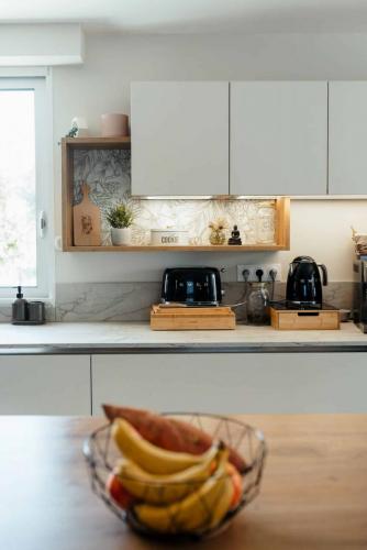Niches ouvertes en bois dans une cuisine rénovée, avec fond à motifs végétaux et objets décoratifs.
