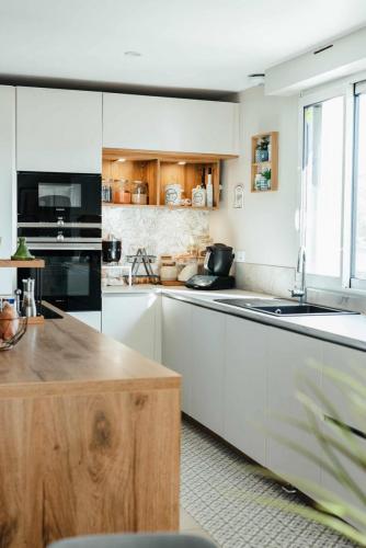 Coin café aménagé dans une cuisine blanche avec électroménager noir, niches en bois et éclairage intégré.