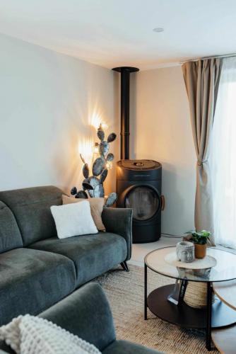 Coin salon chaleureux avec canapé vert profond, poêle à bois noir, luminaire décoratif et tables basses.'                                                                                  